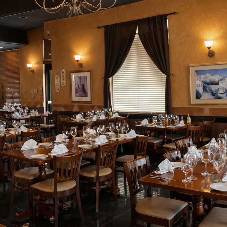 Elegant restaurant dining room with wooden tables, white napkins, wine glasses, framed artwork, and warm lighting.